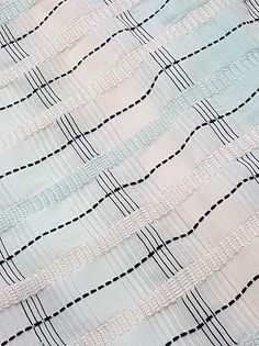 a piece of cloth with black lines on it and some white fabric in the background