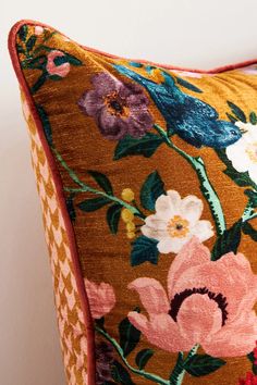 an orange floral pillow with pink and purple flowers on it