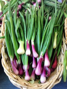 green onions and other vegetables are in a basket