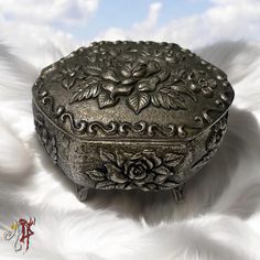 an ornate metal box sitting on top of a white furnishing with clouds in the background