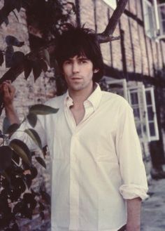 a man standing next to a tree in front of a building