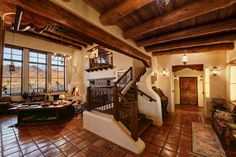 a living room filled with furniture and lots of windows next to a staircase leading up to a second story