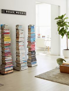 a room filled with lots of books on top of a hard wood floor next to a plant