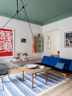 a living room filled with furniture and paintings on the wall next to a blue couch