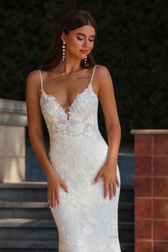 a woman in a wedding dress posing for the camera with her hands on her hips