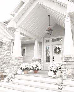 a white house with flowers on the front steps and wreaths around the porch area