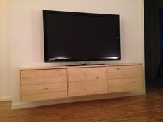 a flat screen tv sitting on top of a wooden cabinet next to a wall mounted television