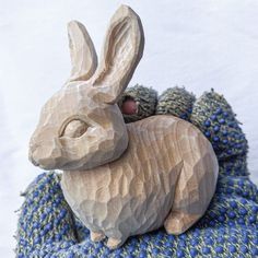 a small wooden rabbit sitting on top of a blanket