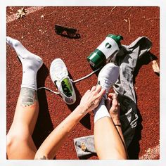 a woman laying on the ground with her feet up next to a pair of tennis shoes