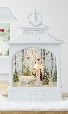 a small white clock with a snowman and deer in the center on a table