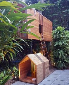 a dog house built into the side of a tree in front of some plants and trees