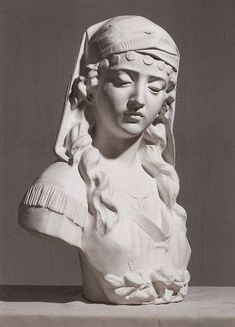 a statue of a woman's head with long braids and a veil on her head