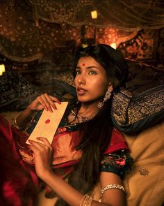 a woman sitting on top of a bed holding a piece of paper in her hand