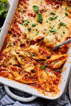 a white casserole dish filled with pasta and spinach garnished with parsley