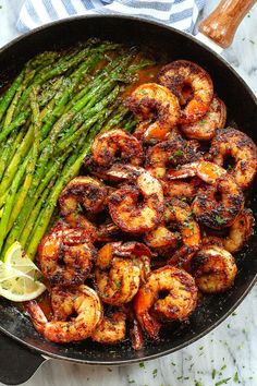 shrimp and asparagus in a skillet with lemon wedges on the side