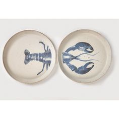 two blue and white plates with lobsters painted on them, one has a crab