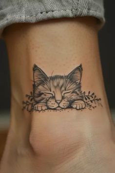 a small kitten tattoo on the side of a woman's leg, with leaves around it