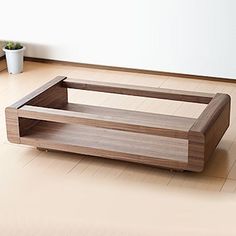 a wooden coffee table sitting on top of a hard wood floor next to a potted plant