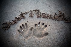 two hands are imprinted in the sand on a beach