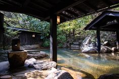 a river flowing through a lush green forest next to a covered area with rocks and trees