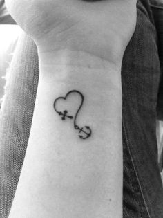 a black and white photo of a person's wrist with a heart tattoo on it