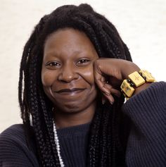 a woman with dreadlocks is smiling for the camera while holding her hand to her face