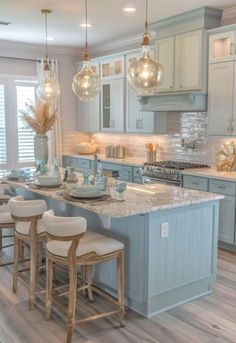 a kitchen filled with lots of counter top space and lights hanging from the ceiling above it