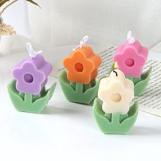 three flower shaped candles sitting next to each other on top of a white tablecloth