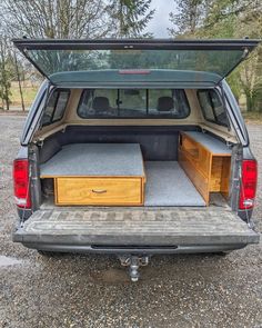 the back end of a vehicle with its trunk open and two wooden drawers in it