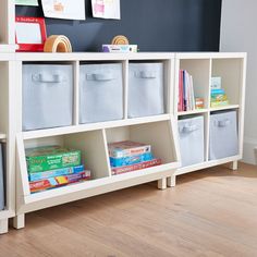 a white shelf with bins filled with books and toys