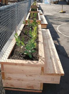 a row of wooden planters sitting on the side of a road next to a fence