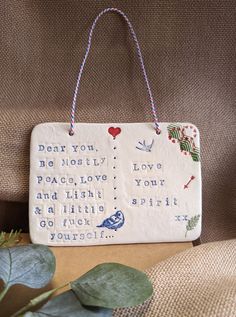 a ceramic sign hanging from the back of a chair next to a potted plant