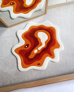 two rugs on the floor with an orange and red design in them, one is shaped like a question mark