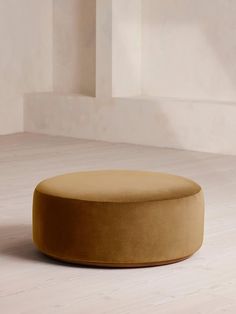 a round ottoman sitting on top of a white floor