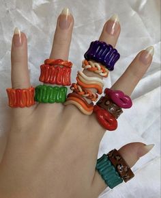 a woman's hand with five different colored rings on her fingers and one is wearing a bear earring