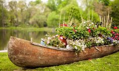 a canoe filled with flowers sitting on top of a lush green field