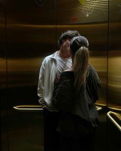 a man and woman standing in front of an elevator with their arms around each other