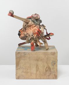 a sculpture is sitting on top of a block of wood and has a baseball bat stuck in it