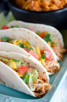 three shredded chicken tacos on a blue plate