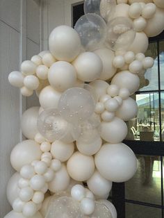 a bunch of white balloons hanging from the side of a building