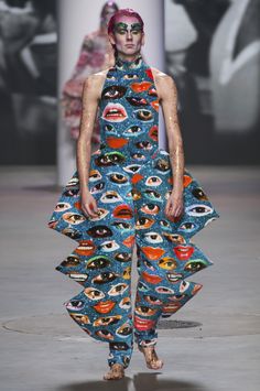 a woman with makeup on her face and eyes is walking down the runway in a blue dress