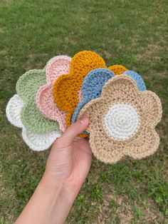 a hand is holding several crocheted flower coasters