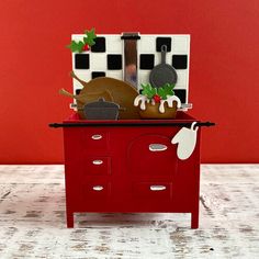 a toy oven with some food in it on a wooden table next to a red wall