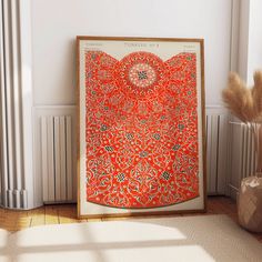 an orange and black art piece sitting on top of a wooden floor next to a window