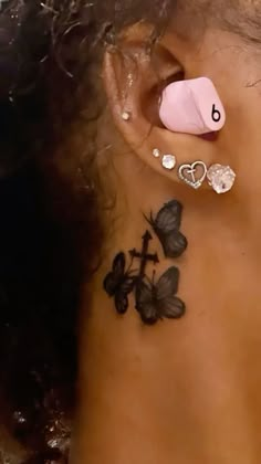 a close up of a person's ear with butterfly tattoos on her left side