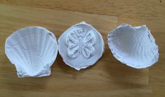 three seashells are sitting on a wooden table