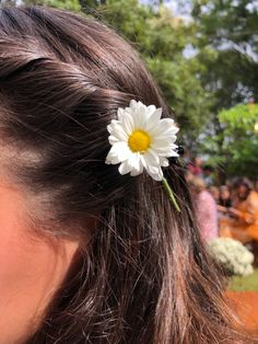 a close up of a person with a flower in their hair and people behind her