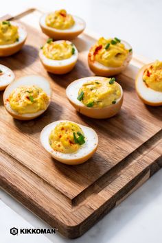 several deviled eggs are arranged on a cutting board