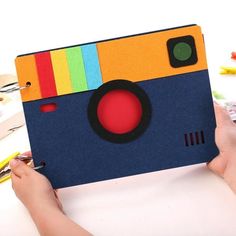 someone is holding up an old camera made out of construction paper and colored pencils