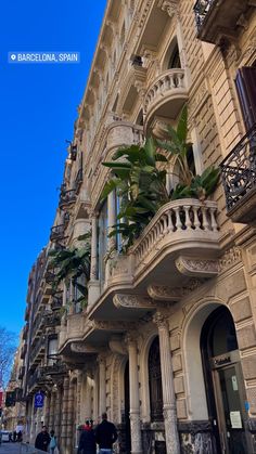 people walking on the sidewalk in front of an old building with balconies and balconyes